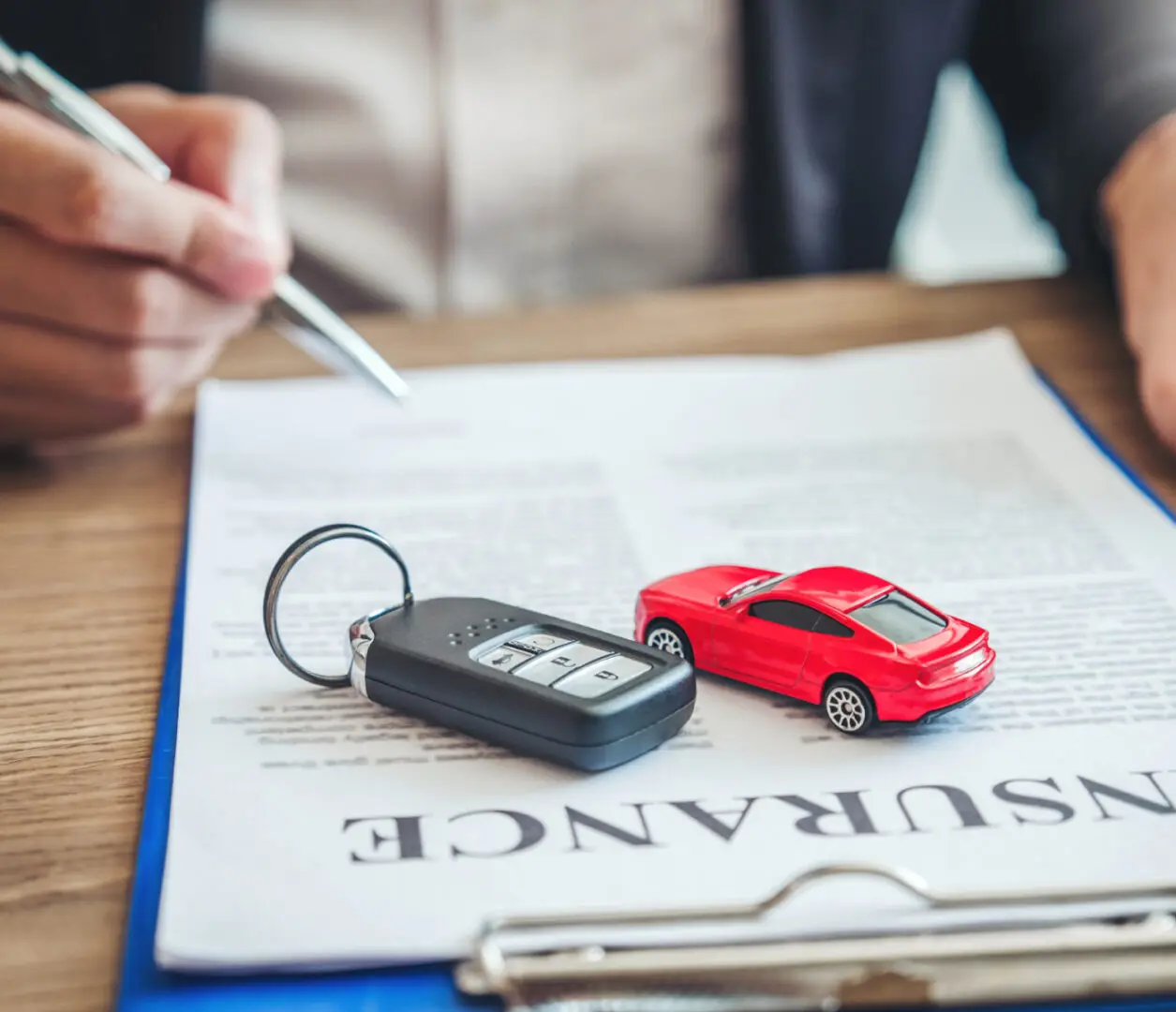 Car keys and toy car on insurance document.